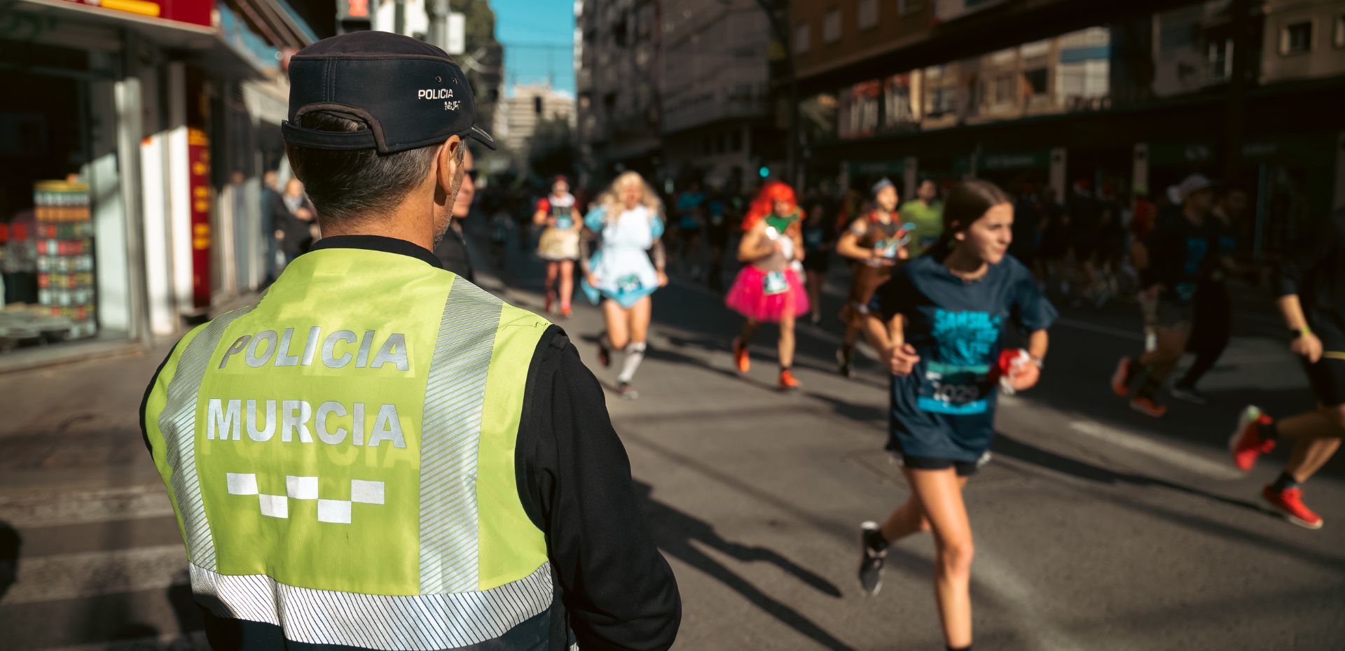 Agente de policía supervisando el desarrollo de la carrera con corredores disfrazados por la Gran Vía