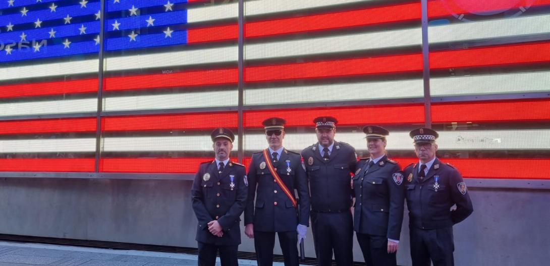 Los 5 participantes de esta policía en el desfile posando junto a la bandera de EEUU de Times Square