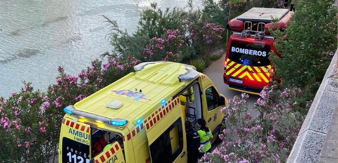 Una ambulancia y vehículo de bomberos dotado de barca en la mota del río durante la intervención