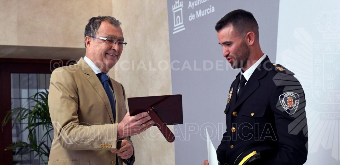 El alcalde muestra al compañero premiado una placa conmemorativa